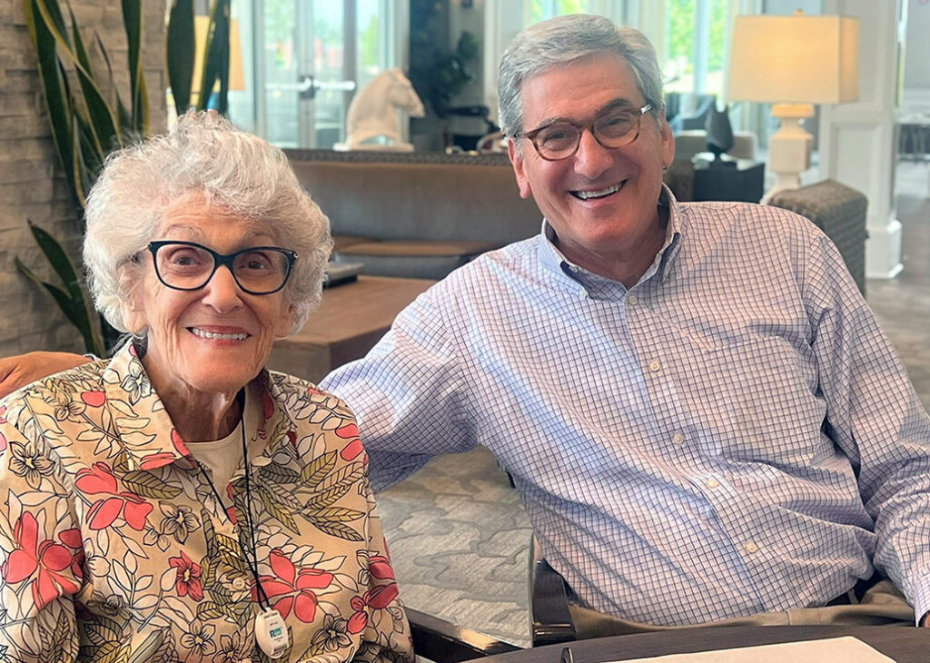 Smiling senior resident and guest sitting together, enjoying a friendly conversation.