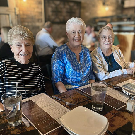 Three senior women smile during a meal out at a local restaurant.