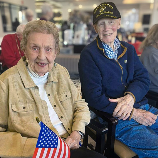 A senior man and woman smile during a patriotic event.