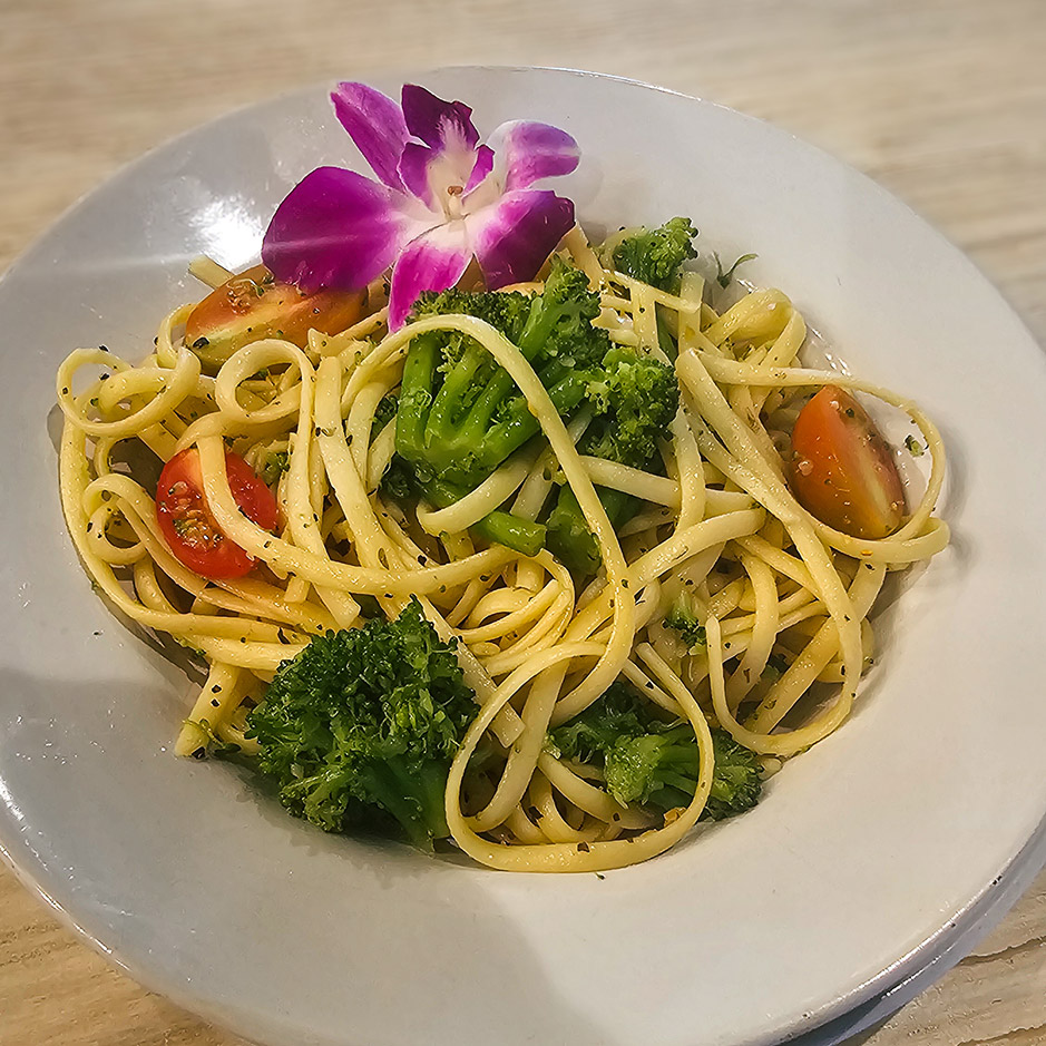 Chef-prepared pasta primavera topped with a delicate purple flower at Vitalia Solon Senior Living.