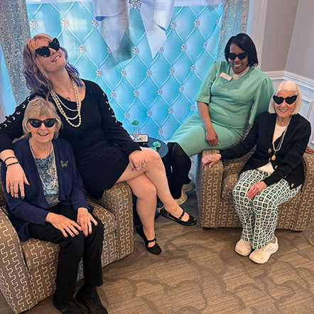 Senior residents and team members at Vitalia Solon pose playfully, wearing sunglasses.